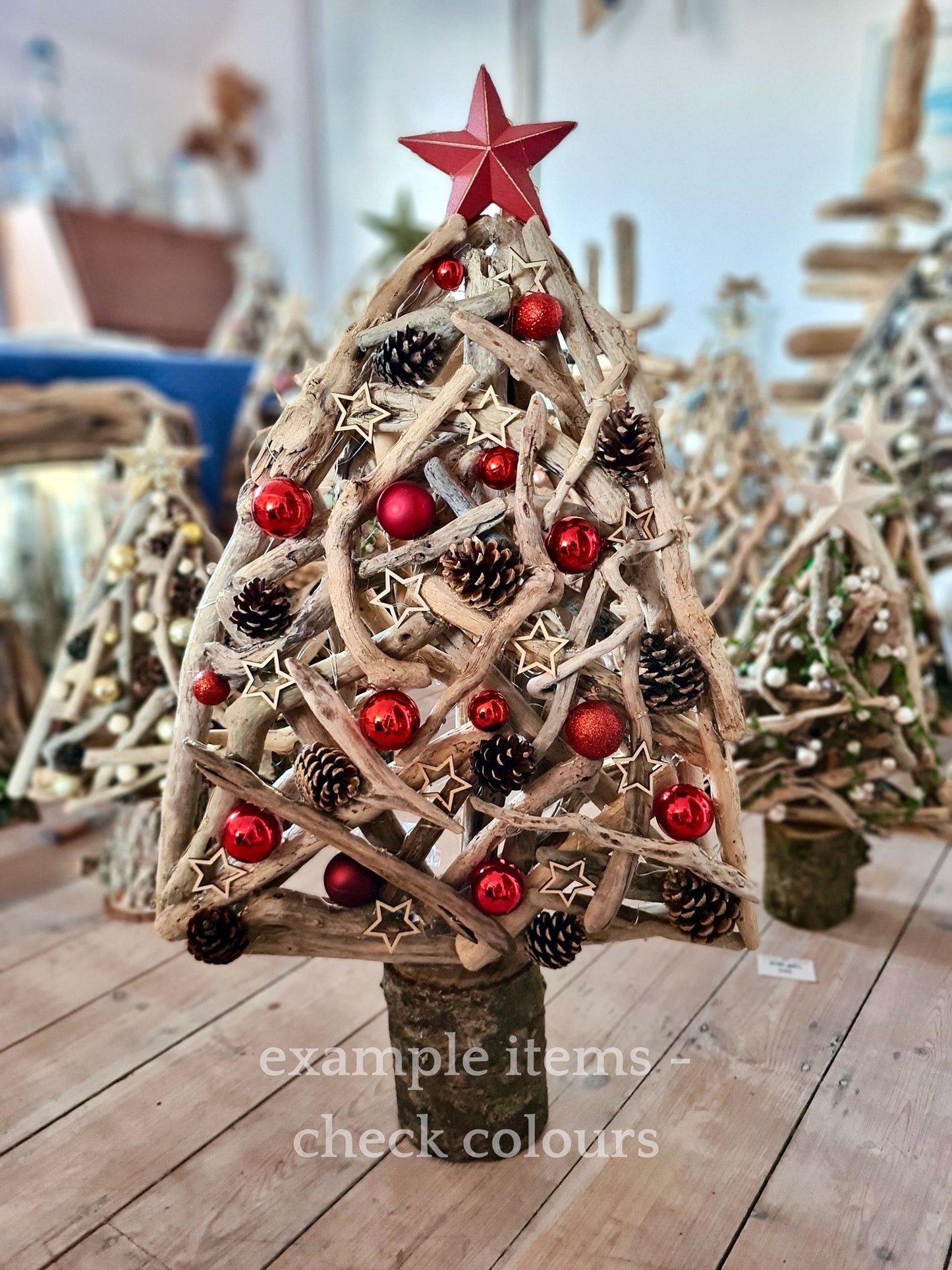 Decorative Christmas tree made of driftwood with red ornaments and a star on top, placed on a wooden surface.
